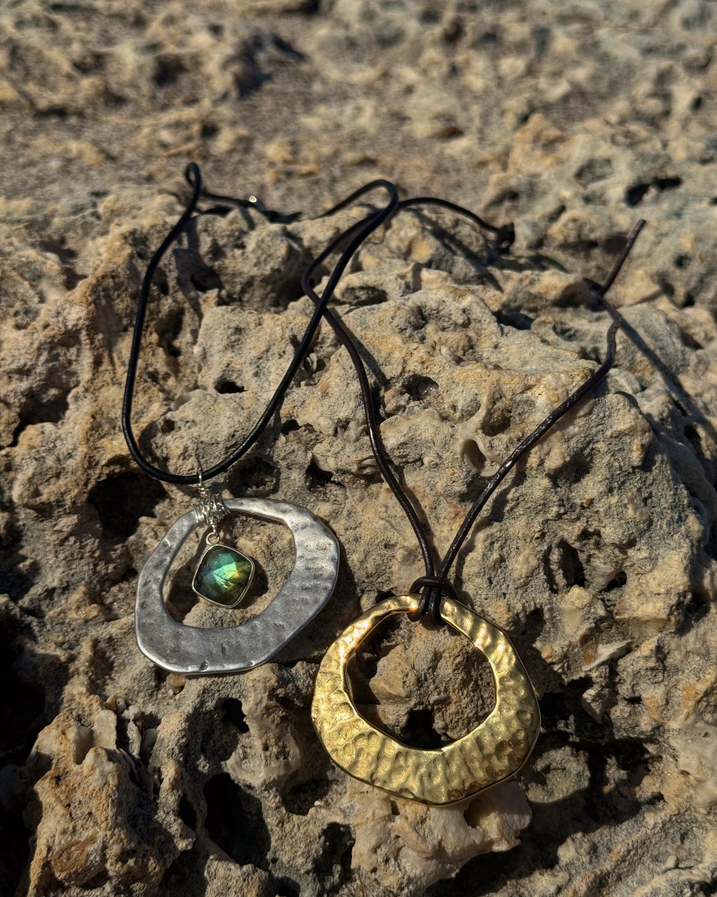 Handmade Aegean Necklace featuring hammered gold or silver pendant on adjustable black or brown leather cord, with optional hand-wrapped gemstone.