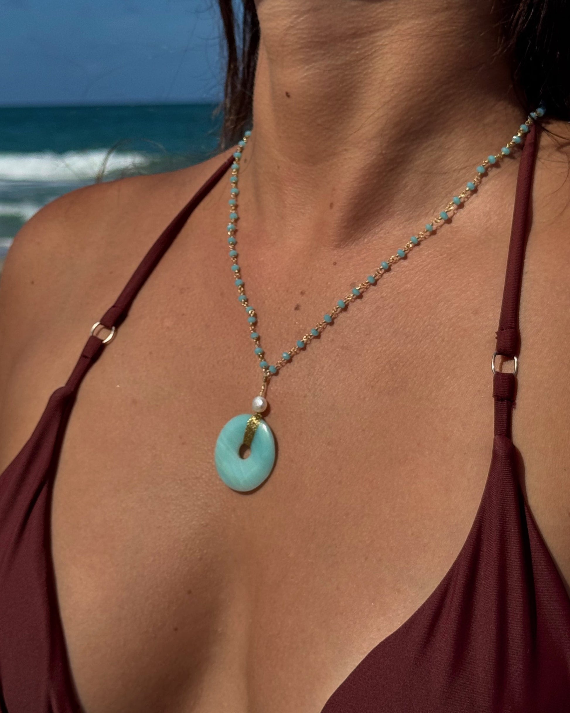 Handmade Luzia Necklace featuring a natural aventurine donut wrapped in gold wire, a freshwater pearl, and a delicate blue beaded chain.