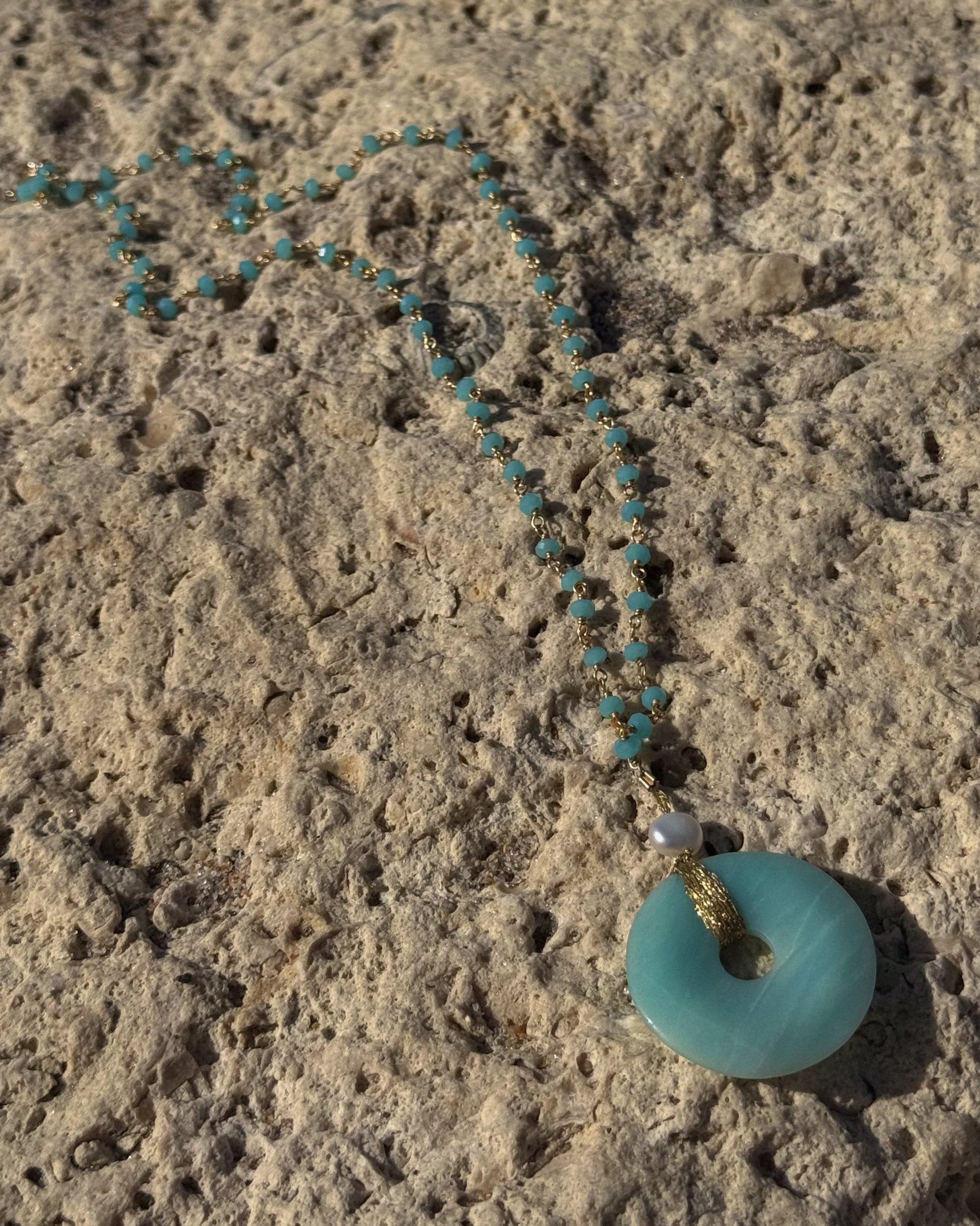 Handmade Luzia Necklace featuring a natural aventurine donut wrapped in gold wire, a freshwater pearl, and a delicate blue beaded chain.