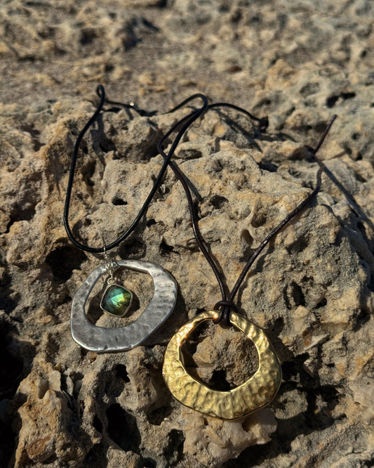 Handmade Aegean Necklace featuring hammered gold or silver pendant on adjustable black or brown leather cord, with optional hand-wrapped gemstone.