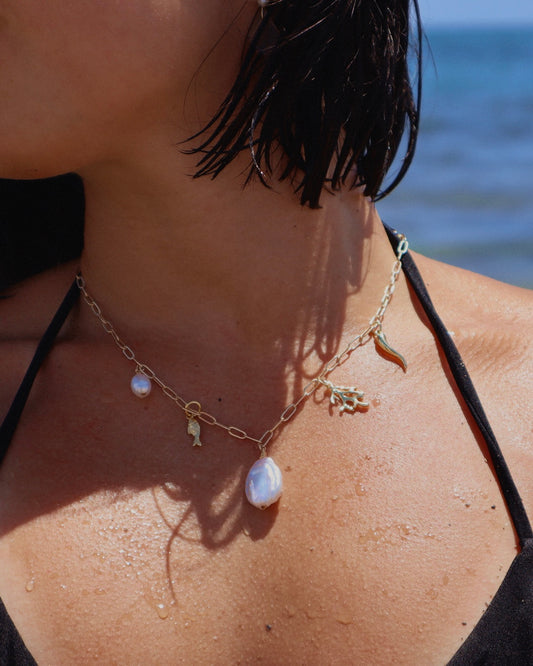 Handmade Indie Mare Charm Necklace featuring freshwater pearls, coral, gold-plated fish, and Italian horn charms on a gold-filled chain, ocean-inspired.