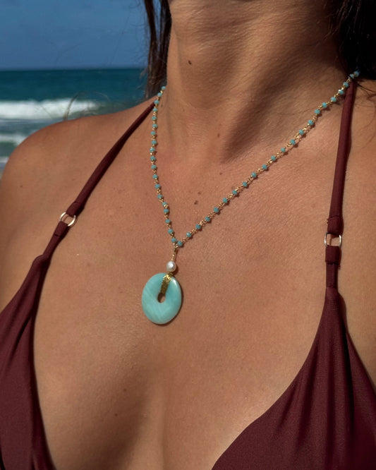 Handmade Luzia Necklace featuring a natural aventurine donut wrapped in gold wire, a freshwater pearl, and a delicate blue beaded chain.